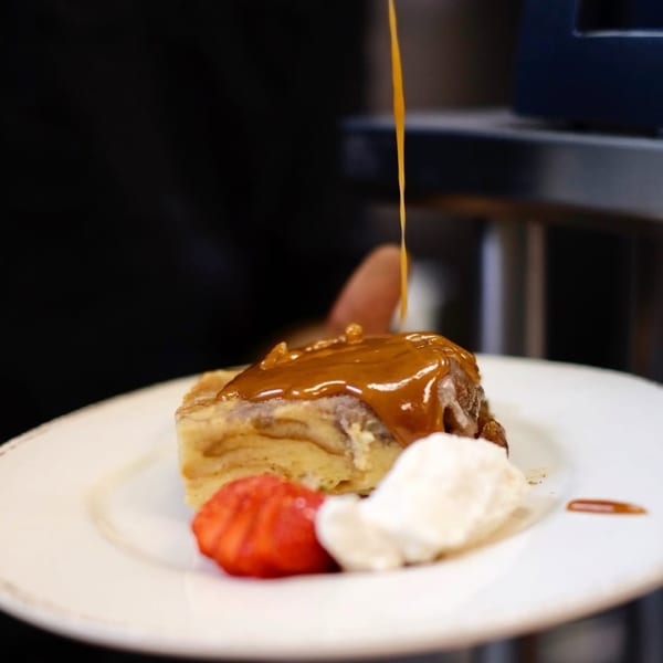 BrewRiver Creole Kitchen's bread pudding with caramel sauce, whipped cream, and a strawberry.